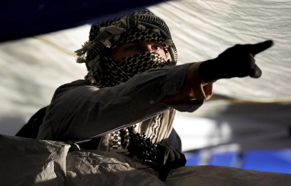 A protester yells at law enforcement officer from behind the barricades erected by pro-Palestinian protesters encamped on the University of Arizona campus, early Wednesday, May 1, 2024 in Tucson, Ariz. (Kelly Presnell/Arizona Daily Star via AP)