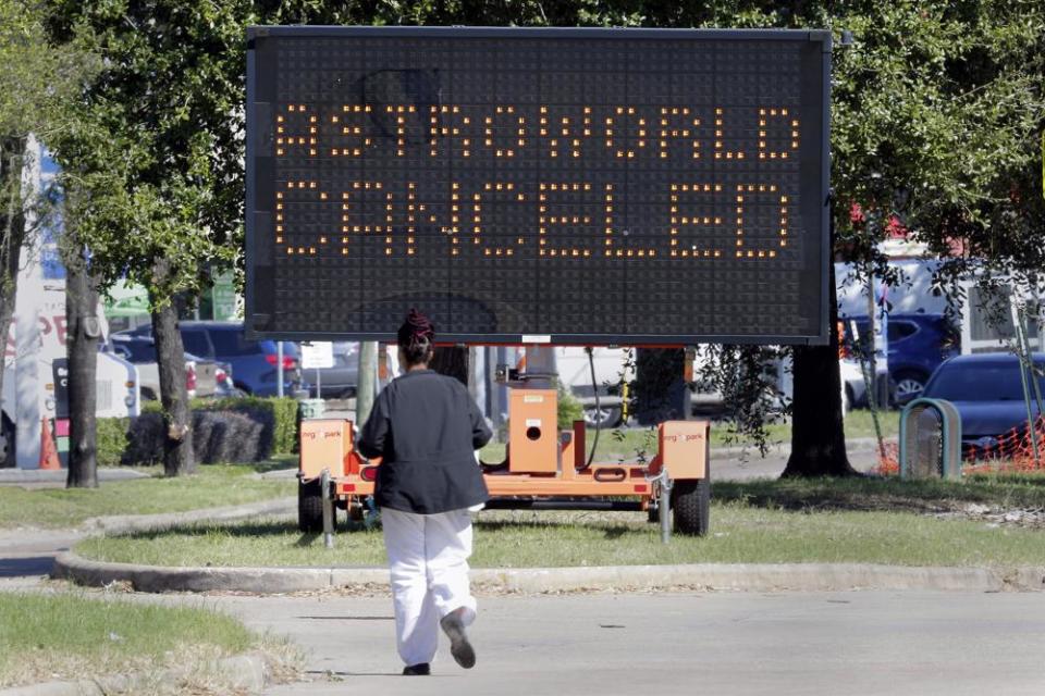 A pedestrian crosses Main Street in front of a sign announcing the cancellation of Astroworld on Nov. 6, 2021, in Houston. (AP Photo/Michael Wyke)