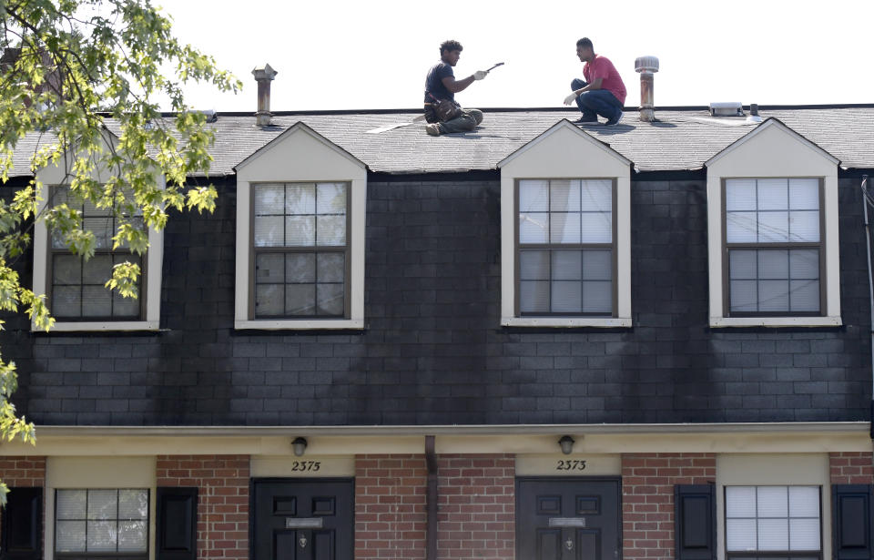 In this Monday, July 29, 2019, photo, men work on a roof at Dutch Village apartments and townhomes, owned by the Kushner Cos., in Baltimore. Jared Kushner’s family real estate firm owns thousands of apartments and townhomes in the Baltimore area, and some have been criticized for the same kind of disrepair and neglect that the president has accused local leaders of failing to address. (AP Photo/Steve Ruark)