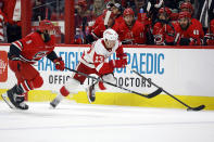 Detroit Red Wings' Lucas Raymond (23) tries to move the puck away from Carolina Hurricanes' Jalen Chatfield (5) during the first period of an NHL hockey game in Raleigh, N.C., Thursday, March 28, 2024. (AP Photo/Karl B DeBlaker)