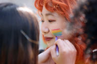 Pride volunteers add rainbow face paint to each other's faces ahead of the Pride in London parade, Saturday, July 2, 2022, marking the 50th Anniversary of the Pride movement in the UK. (James Manning/PA via AP)