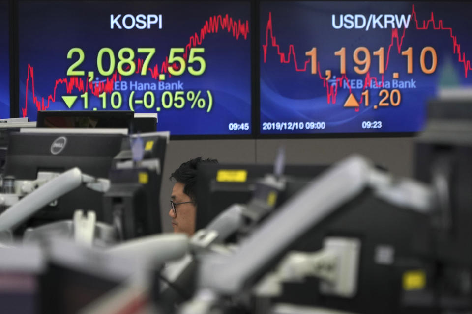 A currency trader watches computer monitors near the screens showing the Korea Composite Stock Price Index (KOSPI), left, and the foreign exchange rate between U.S. dollar and South Korean won at the foreign exchange dealing room in Seoul, South Korea, Tuesday, Dec. 10, 2019. Asian stock markets have fallen as investors look ahead to interest rate decisions by U.S. and European central bankers and possible American tariff hike on Chinese imports. (AP Photo/Lee Jin-man)