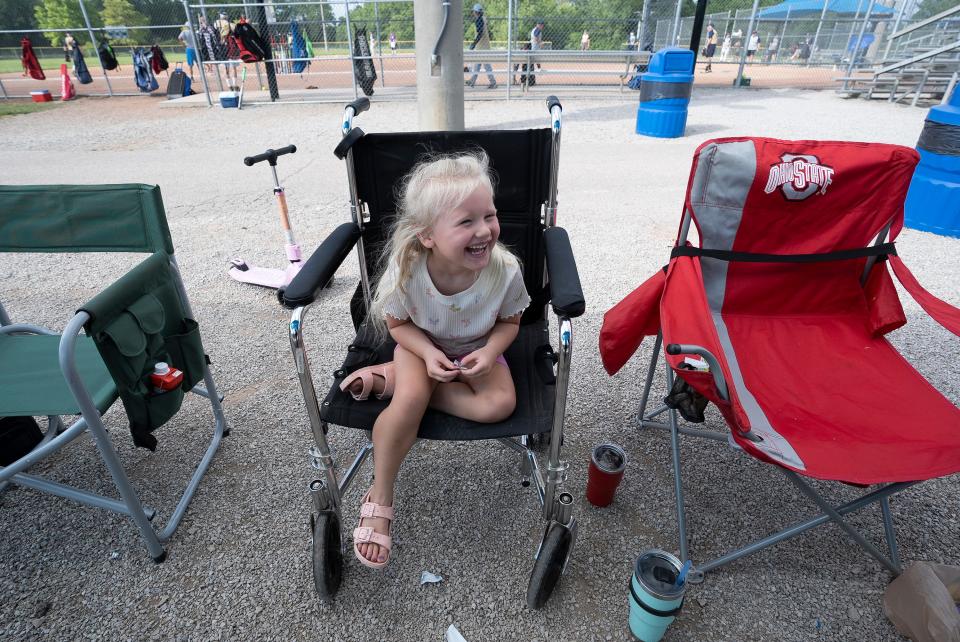 Jul 13, 2023; Hilliard, Ohio, USA;  Emma Bryan, 4, sits in her great-grandfathers wheelchair while she watches the Thursday games of the Central Ohio Senior Softball Association at the Roger A. Reynolds Municipal Park. 