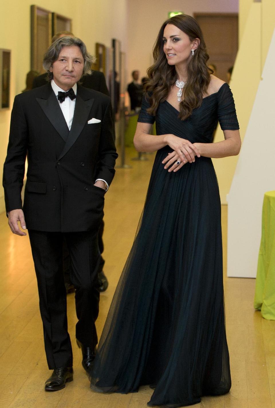 Kate Duchess of Cambridge walks with a guest a fund raising gala at the National Portrait Gallery in London, Tuesday, Feb. 11, 2014. The Duchess is wearing a dress by British designer Jenny Packham and a necklace on loan from Queen Elizabeth II that was given to the Queen as a gift for her wedding in 1947. (AP Photo/Alastair Grant, Pool)