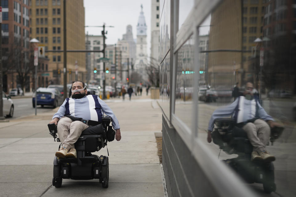 Temple University doctoral student Jaggar DeMarco poses for a portrait while utilizing a battery powered ventilator in Philadelphia, Wednesday, March 6, 2024. “I’m constantly angry that my life and what I can do with (it) is sometimes determined by insurance companies and bureaucracy,” says DeMarco, who has chronic respiratory failure. (AP Photo/Matt Rourke)