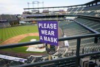 A COVID-19 sign urging fans to wear their masks is threaded through a drink holder in the upper deck of Coors Field before the Colorado Rockies host the Cincinnati Reds in a baseball game, Thursday, May 13, 2021, in Denver. (AP Photo/David Zalubowski)