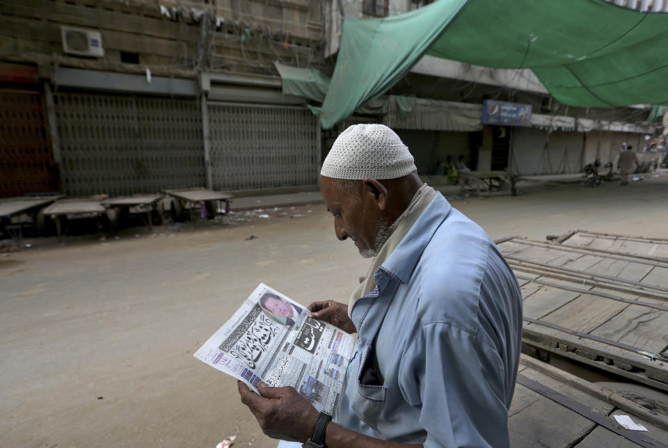 A man reads a copy of morning news paper at a market closed due to strikes called by the the country's religious political parties over the security forces's crackdown against a banned Tehreek-e-Labaik Pakistan party, in Karachi, Pakistan, Monday, April 19, 2021. An outlawed Pakistani Islamist political group freed 11 policemen almost a day after taking them hostage in the eastern city of Lahore amid violent clashes with security forces, the country's interior minister said Monday. (AP Photo/Fareed Khan)