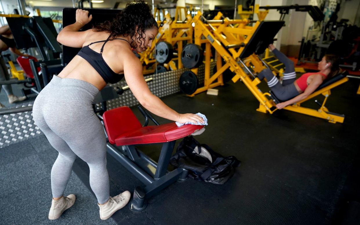 Gym members sanitising equipment after working out - PA