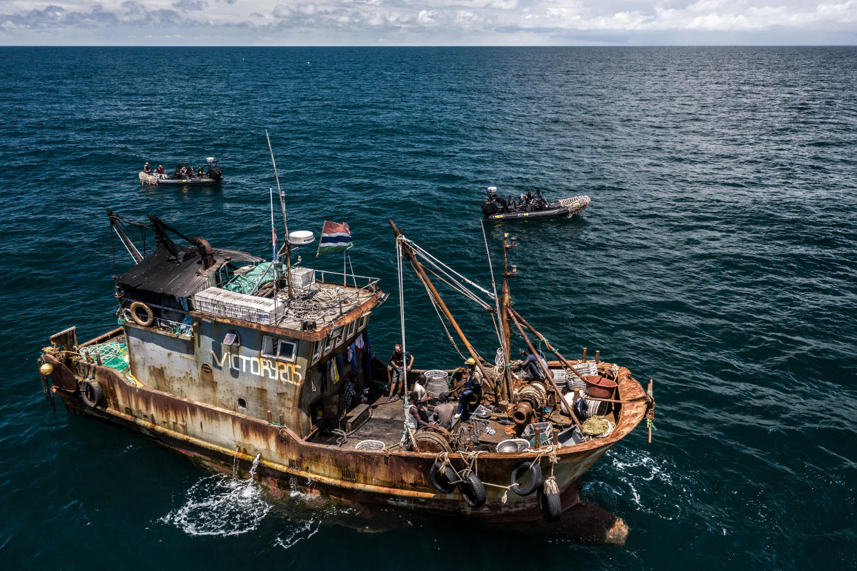 Rusty vessel Victory205 on the sea with two speedboats. (Fábio Nascimento/The Outlaw Ocean Project, Gambia, 2019)