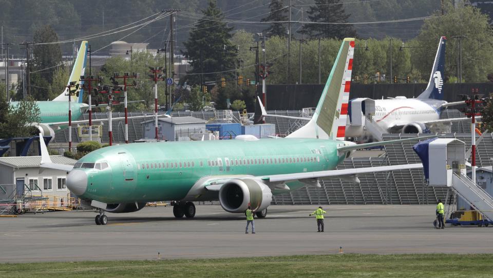 Workers stand near a Boeing 737 MAX 8 jetliner being built for American Airlines prior to a test flight, Wednesday, May 8, 2019, in Renton, Wash. Passenger flights using the plane remain grounded worldwide as investigations into two fatal crashes involving the airplane continue. (AP Photo/Ted S. Warren)