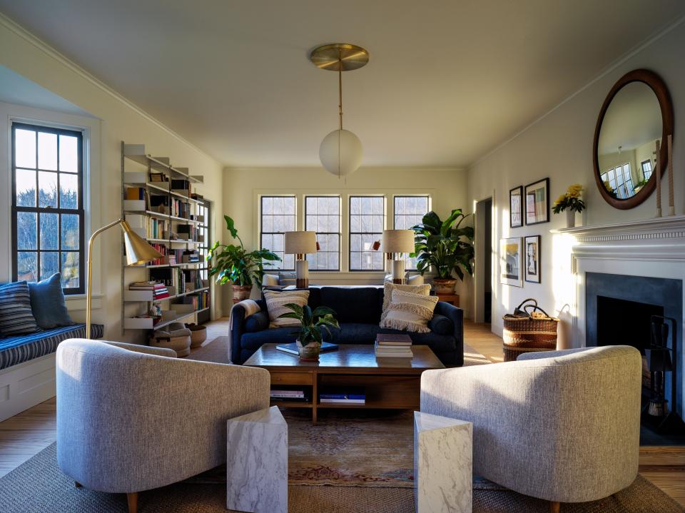 In the living room, CB2 side tables, chairs by Interior Define, a vintage Paul Mccobb cocktail table from Chairish, a Lawson-Fenning sofa, Lightology floor lamp, Stone and Sawyer table lamps, Vitsoe shelves, and a Workstead globe light.