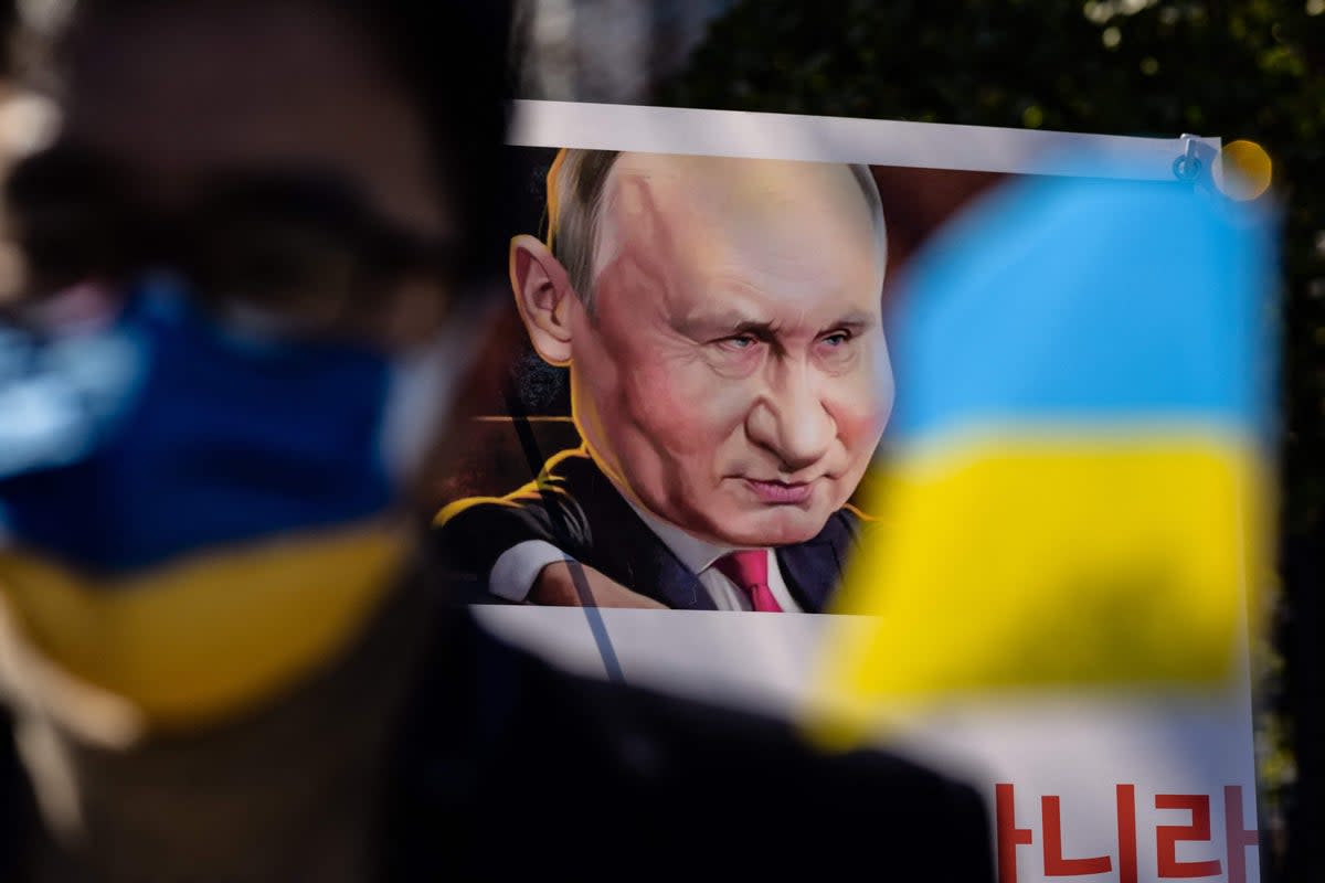 A poster depicting Russian president Vladimir Putin is displayed as people gather during a protest to mark one year since Russia’s invasion of Ukraine, near the Russian embassy in Seoul  (AFP via Getty Images)