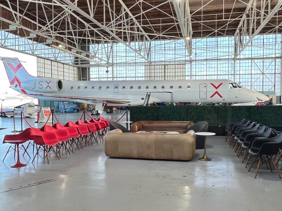 A hangar full of chairs and a white JSX-branded aircraft.