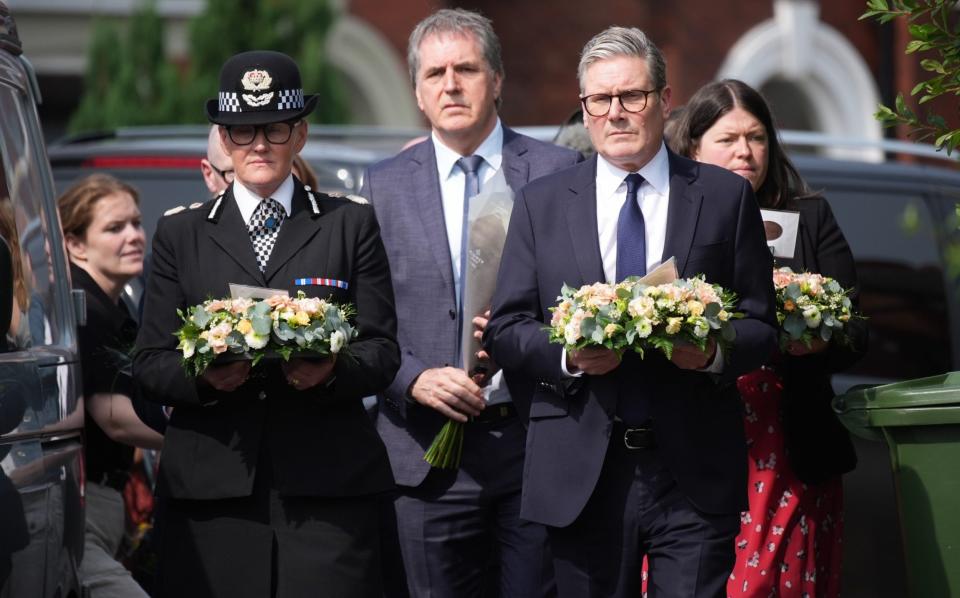 Keir Starmer arrives with a floral tribute to the child victims of a knife attack