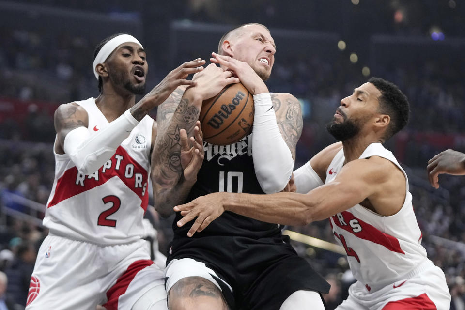 Toronto Raptors forward Jalen McDaniels, left, and forward Garrett Temple, right, try to tie up Los Angeles Clippers center Daniel Theis during the first half of an NBA basketball game Wednesday, Jan. 10, 2024, in Los Angeles. (AP Photo/Mark J. Terrill)