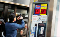 A man photographs a newstand billboard advertising tickets for the $1-billion Mega Millions lottery drawing in New York City, U.S., October 19, 2018. REUTERS/Brendan McDermid