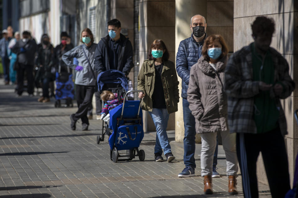 People wearing face-masks line up to buy supplies from a shop during the coronavirus outbreak in Barcelona, Spain, Saturday, April 4, 2020. The new coronavirus causes mild or moderate symptoms for most people, but for some, especially older adults and people with existing health problems, it can cause more severe illness or death. (AP Photo/Emilio Morenatti)