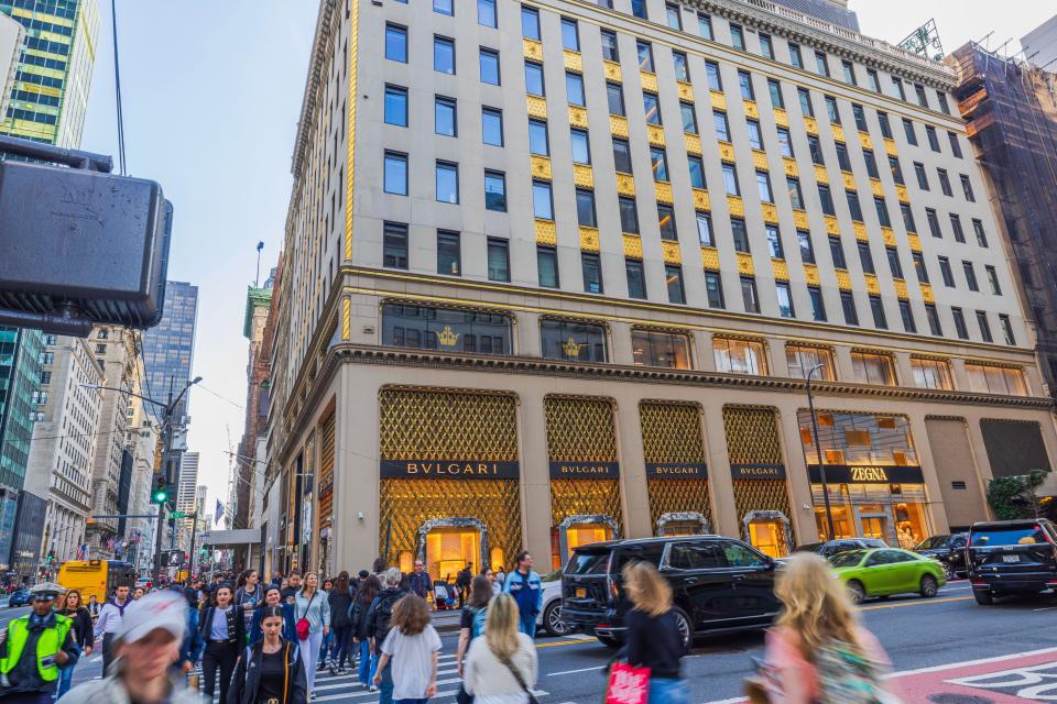 Beautiful view of a bustling street scene on Fifth Avenue in New York City, featuring people walking and luxury shops like Bvlgari and Zegna.