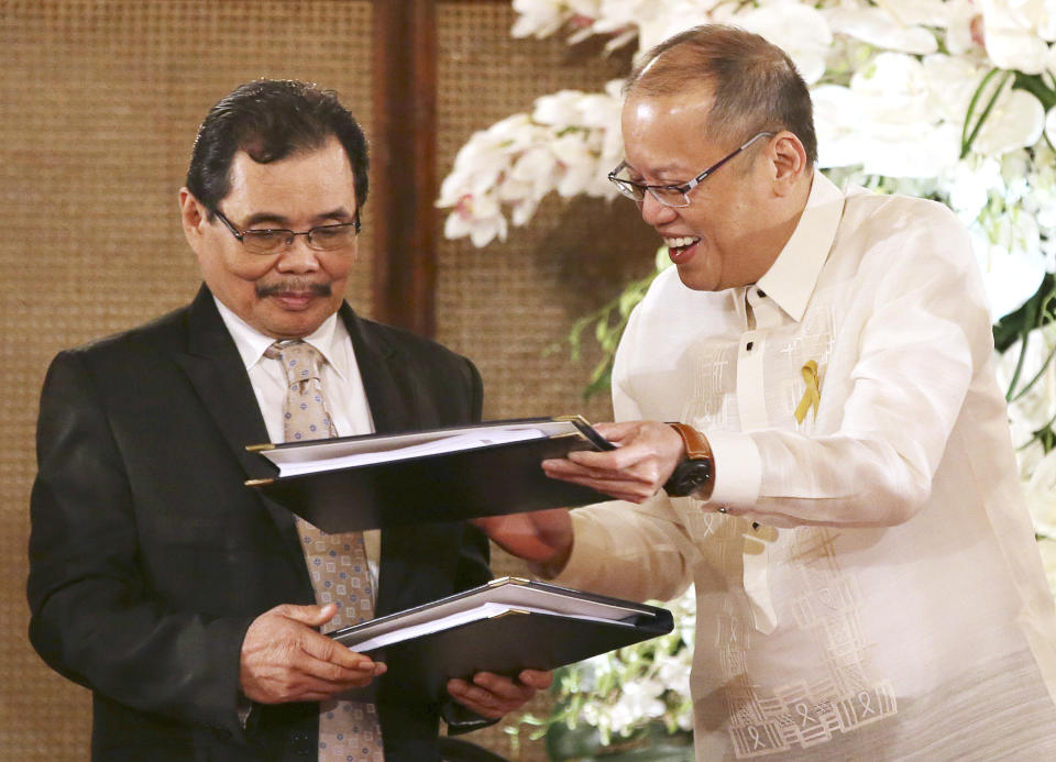 FILE - Philippine President Benigno Aquino III, right, hands over documents to Moro Islamic Liberation Front chief negotiator Mohagher Iqbal during the turnover ceremony of the Draft of the Bangsamoro Basic Law at the Malacanang Presidential Palace in Manila, Philippines on Sept. 10, 2014. Foreign peacekeepers credited with helping ease years of bloody fighting between government forces and Muslim rebels have left the southern Philippines after officials terminated their presence but talks are underway to allow their possible return, officials and the rebels said Friday July 15, 2022. (AP Photo/Aaron Favila, File)