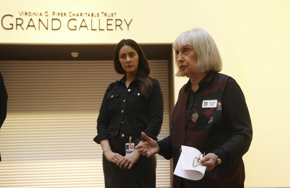 In this Wednesday, Oct. 23, 2019, photo, Heard Museum Director of Research, Dr. Ann Marshall, right, talks about the exhibit of baskets from weavers from the Miwok and Mono Lake Paiute tribes as they are shown with David Hockney's Yosemite artistic work on display at the Heard Museum as Heard Museum Fine Arts Curator, Erin Joyce, left, listens in Phoenix. "David Hockney's Yosemite and Masters of California Basketry" exhibition opens Monday. (AP Photo/Ross D. Franklin)