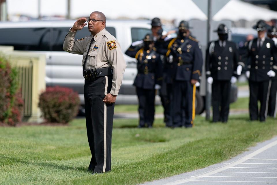 Officers salute as the body of Henderson County sheriff's deputy Ryan Hendrix is carried out of Mud Creek Baptist Church to a waiting fire engine following his funeral service on Sept. 18, 2020. Hendrix died in the line of duty.