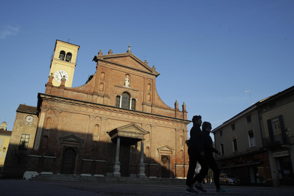 Two people are silhouetted against the sky as they walk in in the center of Codogno, near Lodi in Northern Italy, Friday, Feb. 21,2020. Health officials reported the country's first cases of contagion of COVID-19 in people who had not been in China. The hospital in Codogno is one of the hospitals - along with specialized Sacco Hospital in Milan - which is hosting the infected persons and the people that were in contact with them and are being isolated. (AP Photo/Luca Bruno)