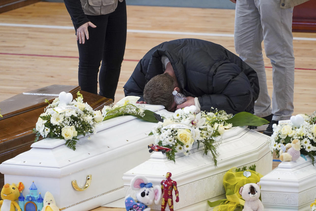 A relative cries on the coffin of one of the victims of last Sunday's shipwreck at the local sports hall in Crotone, southern Italy, Wednesday, March 1, 2023. Nearly 70 people died in last week's shipwreck on Italy's Calabrian coast. The tragedy highlighted a lesser-known migration route from Turkey to Italy for which smugglers charge around 8,000 euros per person. (Antonino Durso/Lapresse via AP, File)
