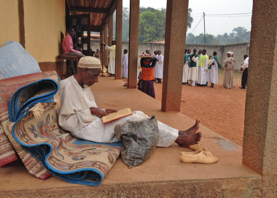 In this photo taken on Sunday, Feb. 23, 2014, A Muslim man reads religions script at a Catholic church in Carnot a town 200 kilometers (125 miles) from the Cameroonian border, in, Central African Republic. The Christian militiamen knew hundreds of Muslims were hiding at the Catholic church and came with their ultimatum: Evict the families to face certain death or else the entire place would be burned to the ground. (AP Photo/Steve Niko)