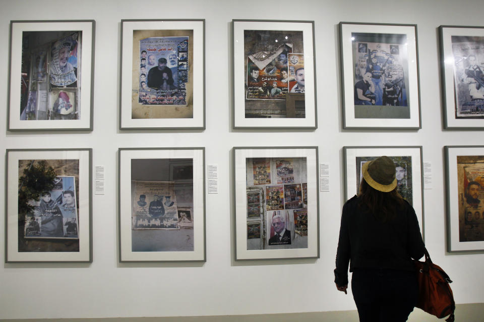 A visitor views photos by Palestinian photographer Ahlam Shibli, at the Jeu de Paume museum in Paris, Wednesday June 12, 2013. The exhibit which started last week at the Jeu de Paume, features dozens of photographs with captions that glorify dead members of Palestinian groups. (AP Photo/Remy de la Mauviniere)