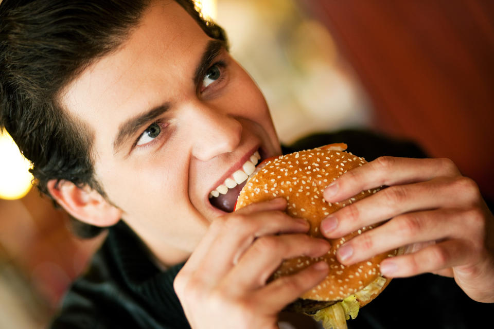 A man takes a bite out of a burger.