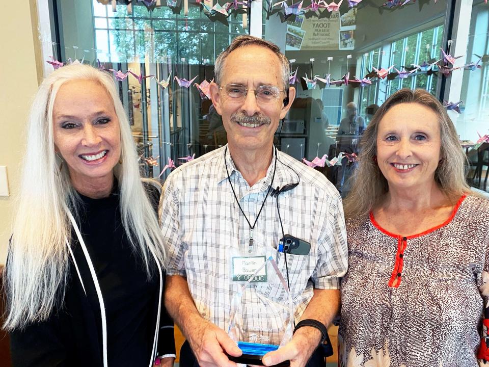 Laura Christenbury, left, and Charlotte Bowers Cunningham, right, present Martin Bauer with his Outstanding Construction Award from Habitat International.