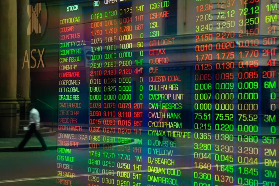 Sydney, Australia - March 5, 2014: An office worker crossing a road is reflected in the glass display of a trading screen at the Australian Stock Exchange on Bridge Street.