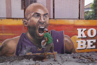 A man work beside a painting of former NBA basketball player Kobe Bryant at the "House of Kobe" basketball court in Valenzuela, north of Manila, Philippines on Monday, Jan. 27, 2020. (AP Photo/Aaron Favila)