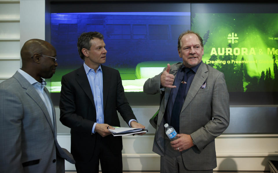 Terry Booth, chief executive officer of Aurora Cannabis Inc., right, gestures while speaking with Cam Battley, chief corporate officer of Aurora Cannabis Inc., center, during a news conference at the Toronto Stock Exchange (TSX) in Toronto, Ontario, Canada, on Monday, May 14, 2018. Aurora Cannabis Inc. agreed to buy rival MedReleaf Corp. for about C$2.9 billion ($2.3 billion) in stock, the companies said Monday in a statement. The deal will create a producer with the capacity to grow 570,000 kilos (1.26 million pounds) a year of cannabis at nine facilities in Canada and two in Denmark. Photographer: Cole Burston/Bloomberg via Getty Images