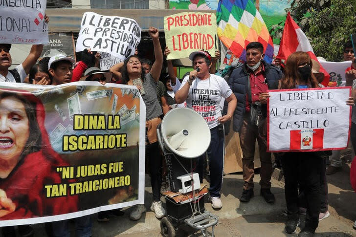 Personas sostienen pancartas mientras los partidarios del destituido presidente peruano Pedro Castillo se reúnen frente a la prisión policial donde está detenido, en Lima,