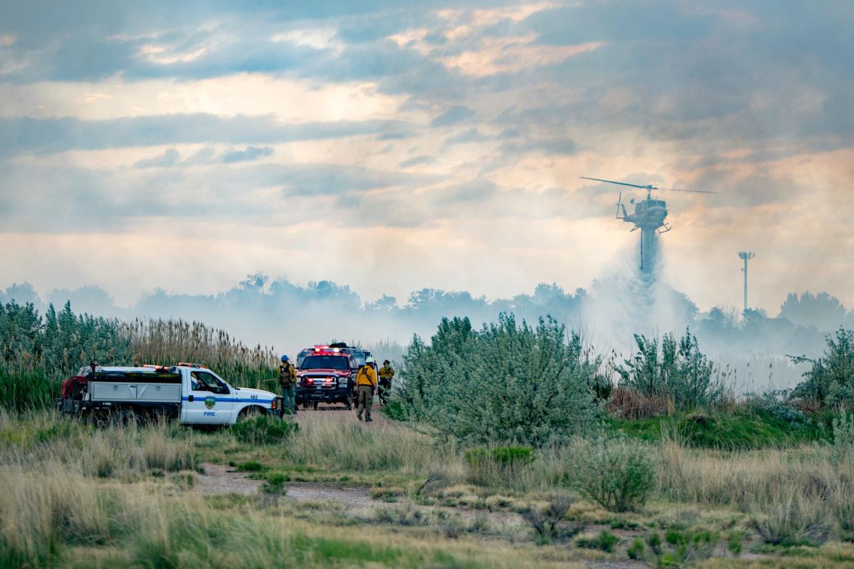 A helicopter drops water on a fire burning near Lake Minnequa in Pueblo, Colo., on Thursday, June 2, 2022.