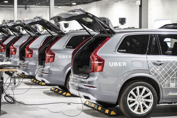 A line of Uber's autonomous SUVs with their trunks open.