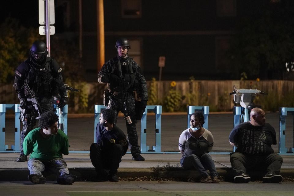 Police hold four people on the street Friday, Oct. 9, 2020, in Wauwatosa, Wis. On Wednesday, District Attorney John Chisholm refused to issue charges against Wauwatosa Police Officer Joseph Mensah for the Feb. 2 fatal shooting of 17-year-old Alvin Cole at Mayfair Mall. (AP Photo/Morry Gash)