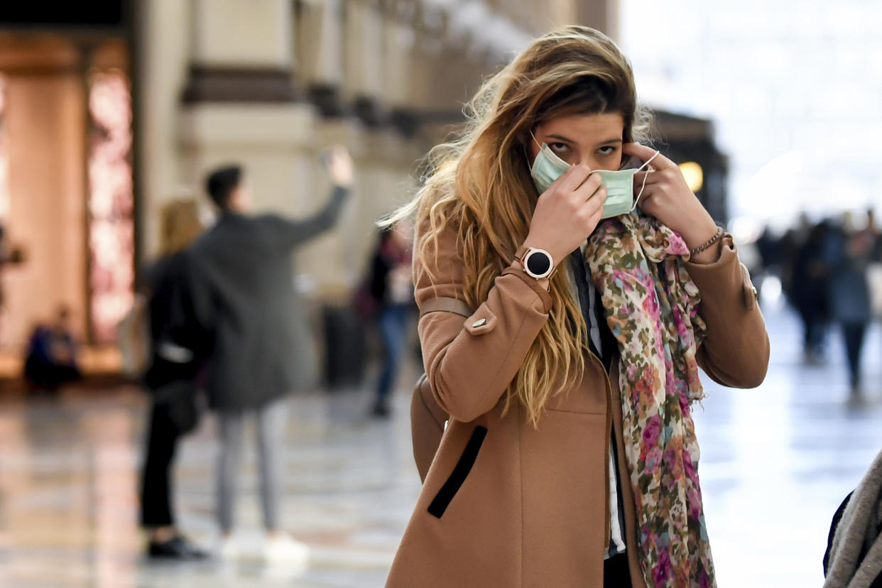 A woman wearing a sanitary mask walks through a shopping area in Milan, Italy, Monday, Feb. 24, 2020. At least 190 people in Italy’s north have tested positive for the COVID-19 virus and four people have died, including an 84-year-old man who died overnight in Bergamo, the Lombardy regional government reported. (Claudio Furlan/Lapresse via AP)