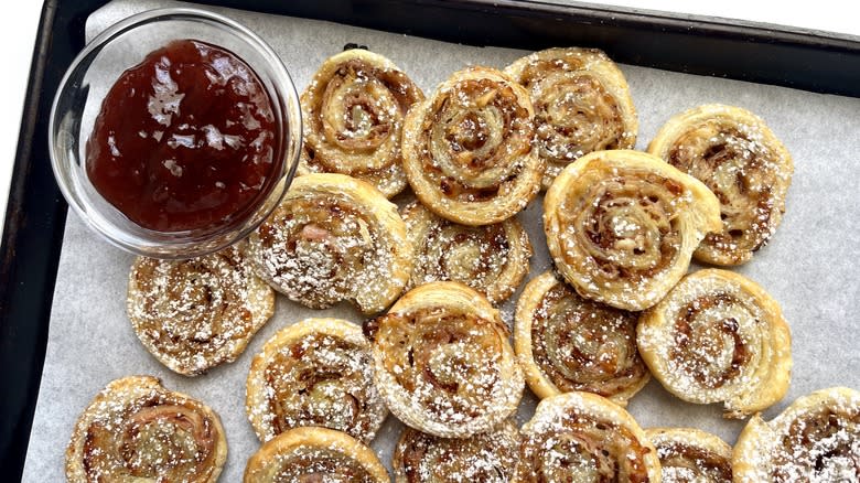 Monte Cristo Pinwheels on a baking sheet with a bowl of strawberry jam