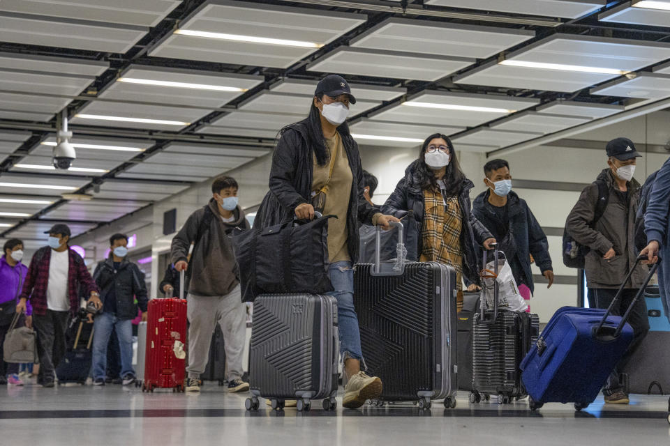 Travelers wearing face masks with their luggage head to the immigration counter at the departure hall at Lok Ma Chau station following the reopening of crossing border with mainland China, in Hong Kong, Sunday, Jan. 8, 2023. Travelers crossing between Hong Kong and mainland China, however, are still required to show a negative COVID-19 test taken within the last 48 hours, a measure China has protested when imposed by other countries. (AP Photo/Bertha Wang)