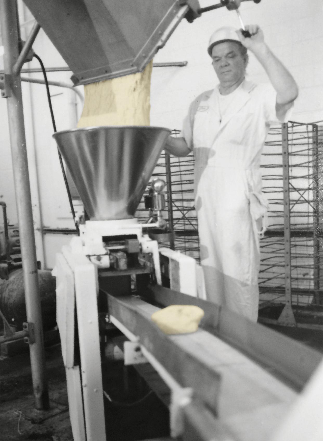 An archival photo of a DeIorio's employee running dough through a bread divider.