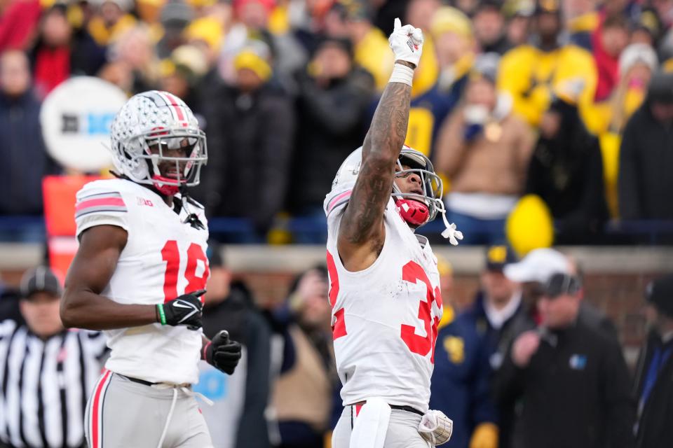 Nov 25, 2023; Ann Arbor, Michigan, USA; Ohio State Buckeyes running back TreVeyon Henderson (32) celebrates a touchdown in front of wide receiver Marvin Harrison Jr. (18) during the NCAA football game against the Michigan Wolverines at Michigan Stadium. Ohio State lost 30-24.