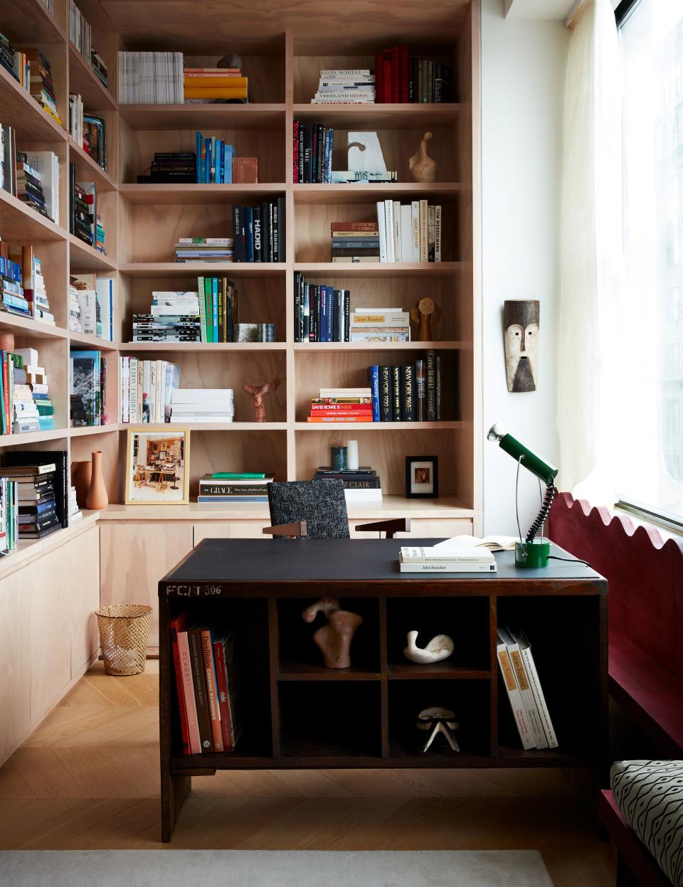 Valle lined a corner of the living room with bookshelves. Pierre Jeanneret desk; André Sornay desk chair from Donzella, and 1970s Italian desk lamp from George Champion. The metal wastebasket is by Mathieu Matégot, and a photograph of Yves Saint Laurent’s office by Gilles Bensimon sits on a shelf behind the desk.