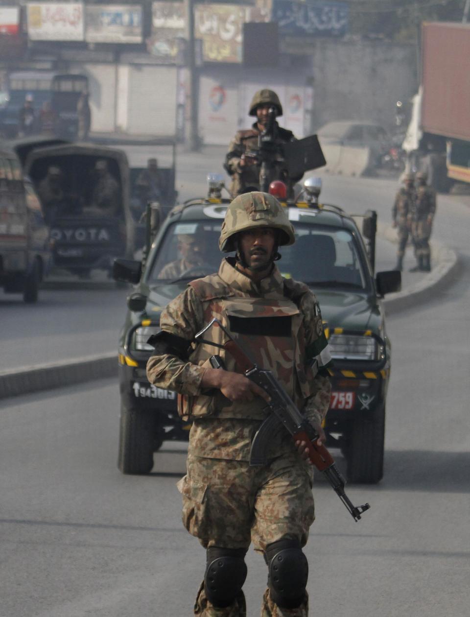 Pakistani army troops secure a road leading to the site of a suicide bombing in Rawalpindi, Pakistan on Monday, Jan. 20, 2014. A suicide bomber blew himself up not far from Pakistan's military headquarters Monday, killing some people a day after a Taliban bombing inside an army compound in the northwest of the country killed many troops, officials and militants said. (AP Photo/Anjum Naveed)