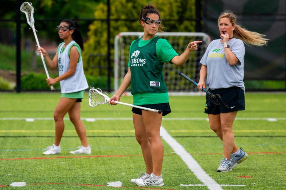 Coach Patricia Alexander, right, leads her girls’ lacrosse team, that includes her daughter Taylor Alexander, center, during a practice at Cardinal Gibbons High School on Wednesday, May 8, 2024.