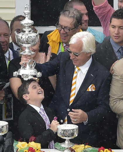 Bob Baffert holds the Woodlawn Vase over his son Bode's head after winning the Preakness. (AP)
