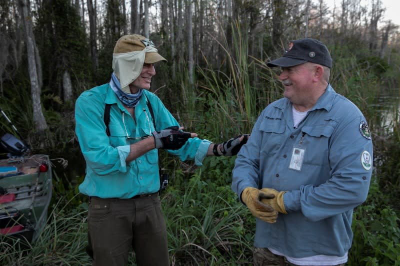 Thomas Aycock talks with a fellow hunter as they explore the Everglades' swamps looking for Burmese pythons, in Ochopee