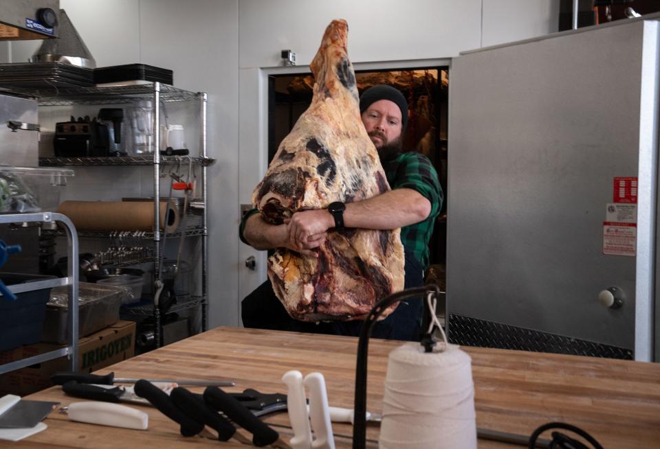 Dustin Dahlin carries a beef round at Underbelly Meat Co. in Phoenix on Dec. 12, 2022.