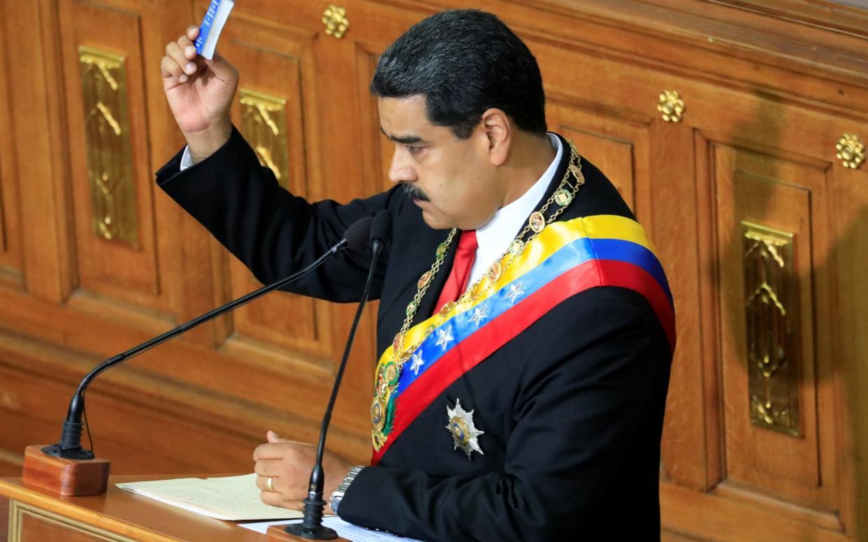 Venezuela's President Nicolas Maduro holds a copy of the National Constitution while he takes oath as re-elected President - REUTERS